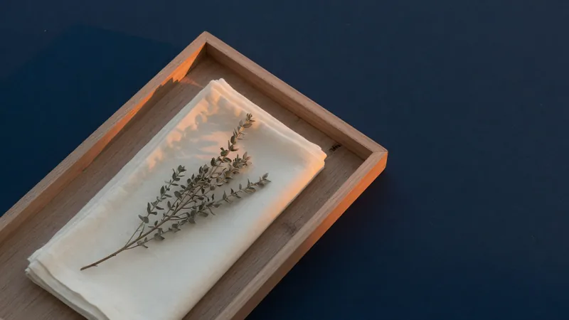 Wooden tray with a folded ivory napkin and a dried herb sprig at dusk