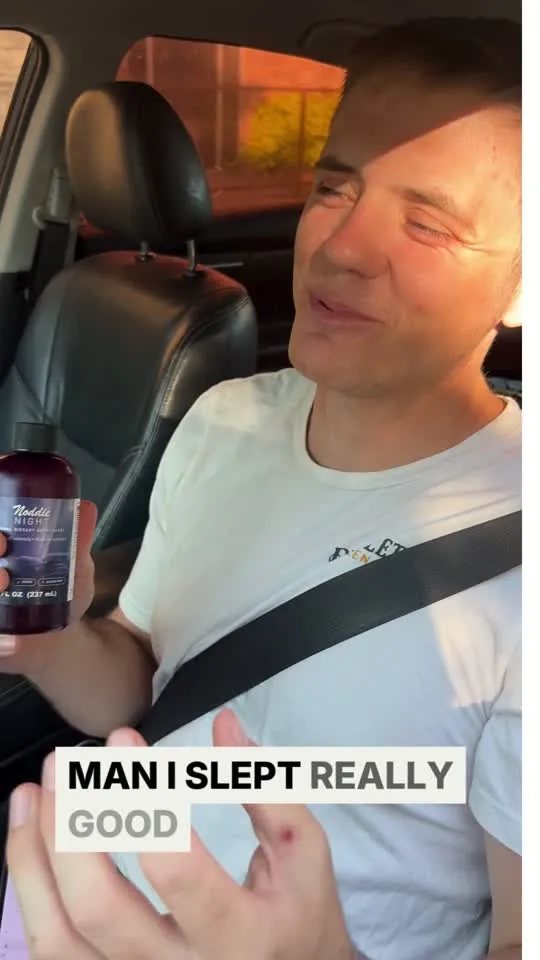 Jacob talking to the camera from the driver's seat, holding a bottle of Noddie Night.
